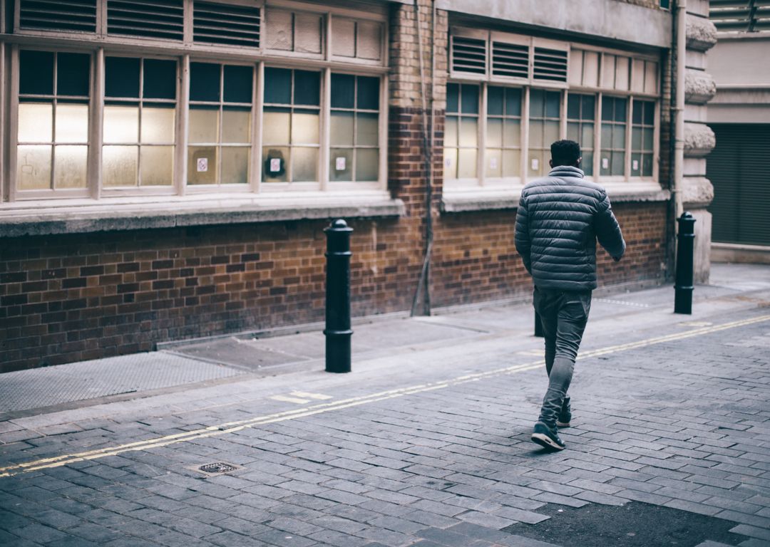 Man Walking Down Urban Alley on Overcast Day