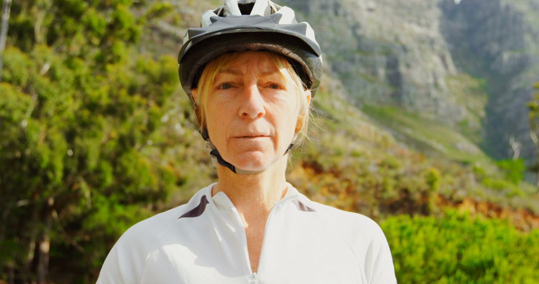 Middle-aged woman cyclist wearing helmet in mountainous terrain - Free Images, Stock Photos and Pictures on Pikwizard.com