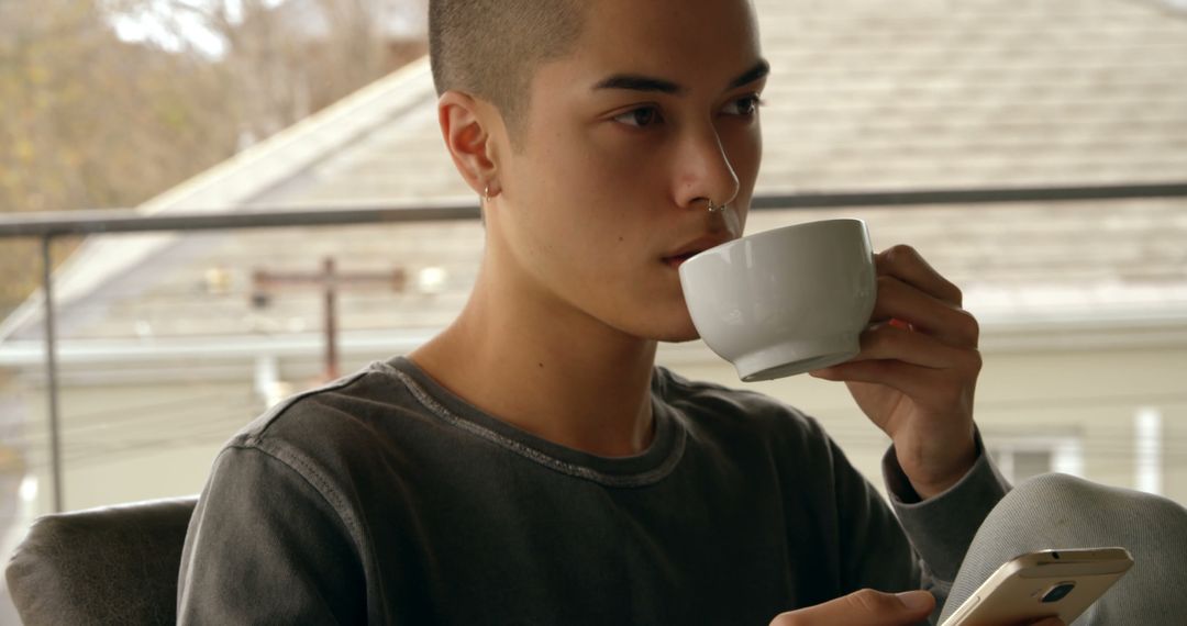 Young Man Drinking Coffee and Browsing Smartphone Outdoors - Free Images, Stock Photos and Pictures on Pikwizard.com