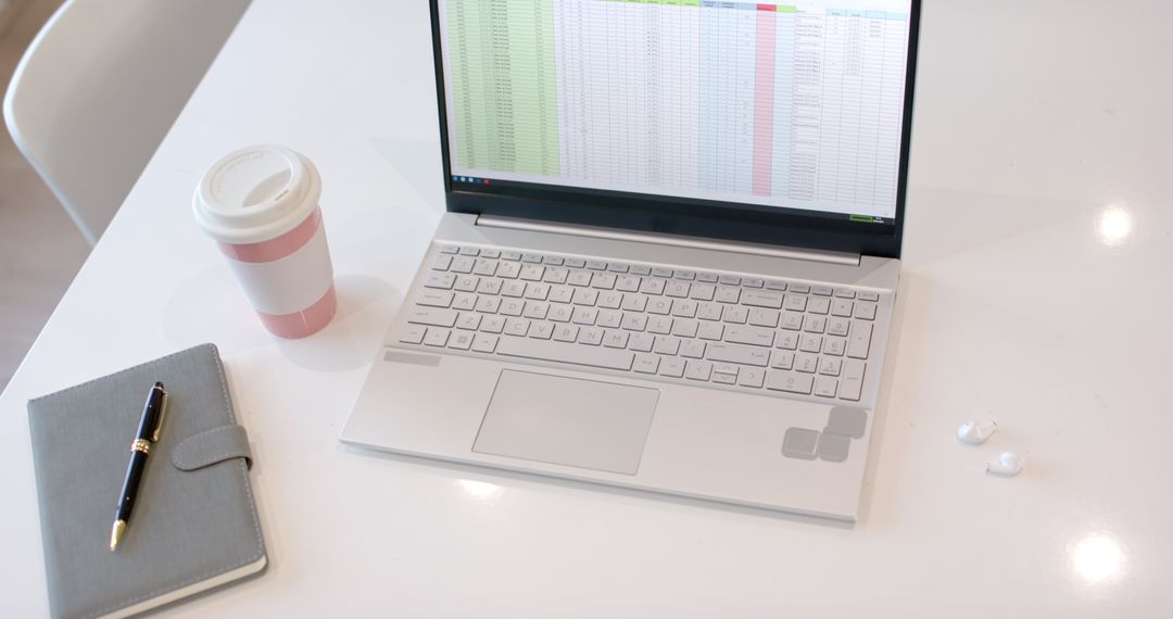 Organized Workspace Featuring Laptop with Spreadsheet and Coffee
