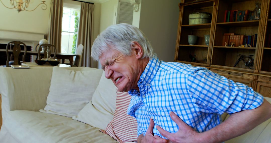 Senior man suffering from chest pain in living room at home - Free Images, Stock Photos and Pictures on Pikwizard.com