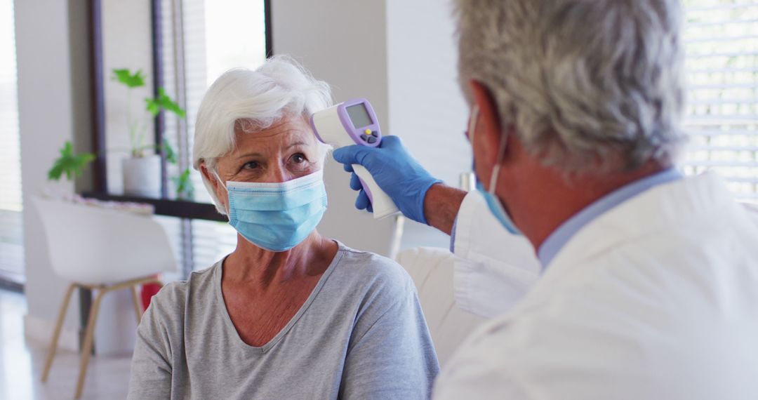 Healthcare Worker Using Infrared Thermometer on Senior Woman - Free Images, Stock Photos and Pictures on Pikwizard.com