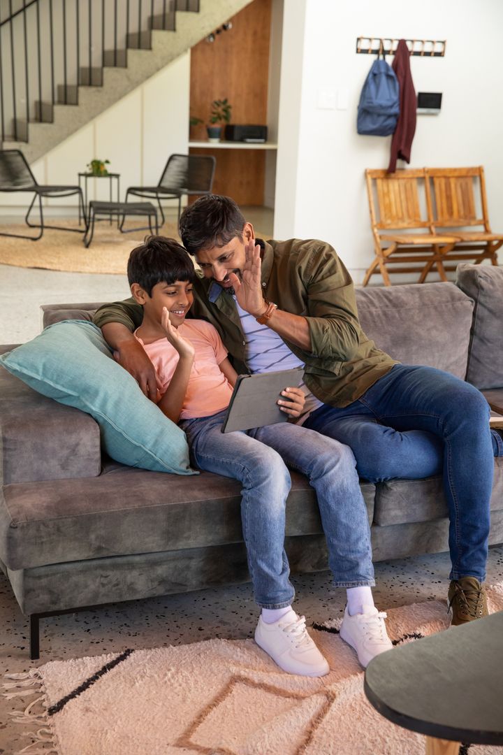 Father and Son Using Tablet for Video Call in Cozy Living Room