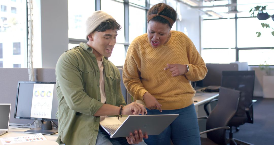 Diverse coworkers collaborating on laptop with charts and analytics in modern open office