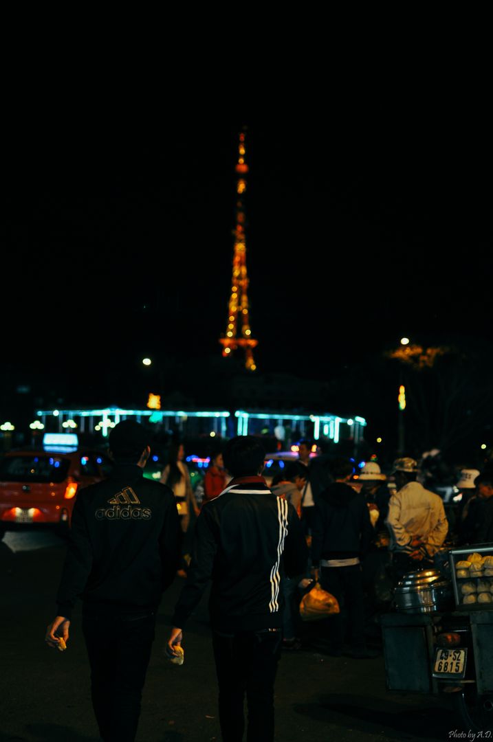 Two Men Walking Through Night Market with Illuminated Tower Background - Free Images, Stock Photos and Pictures on Pikwizard.com