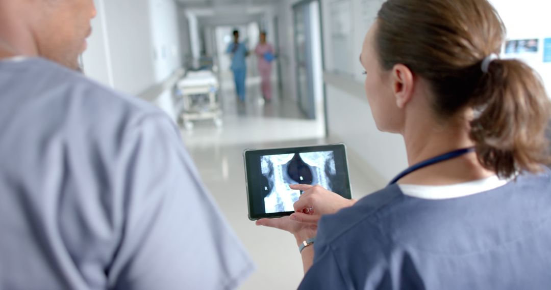 Doctors Analyzing Medical Imaging on Tablet in Hospital Corridor - Free Images, Stock Photos and Pictures on Pikwizard.com