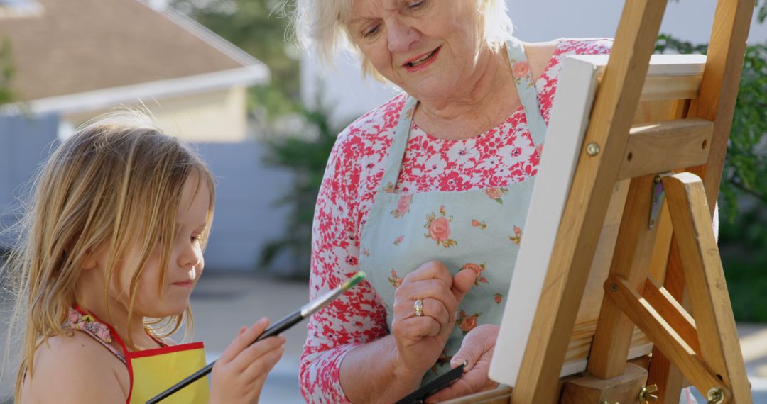 Grandmother Teaching Granddaughter to Paint on Easel Outdoors - Free Images, Stock Photos and Pictures on Pikwizard.com