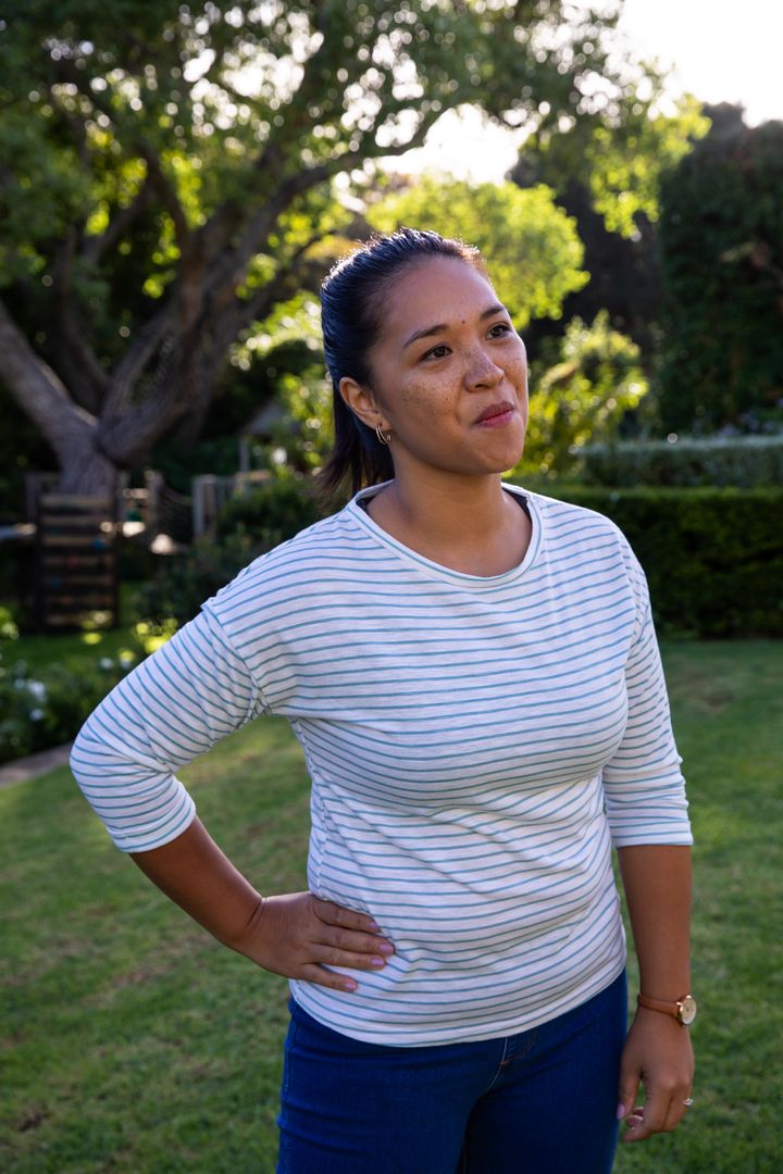 Smiling Woman Relaxing on Sunlit Backyard Lawn