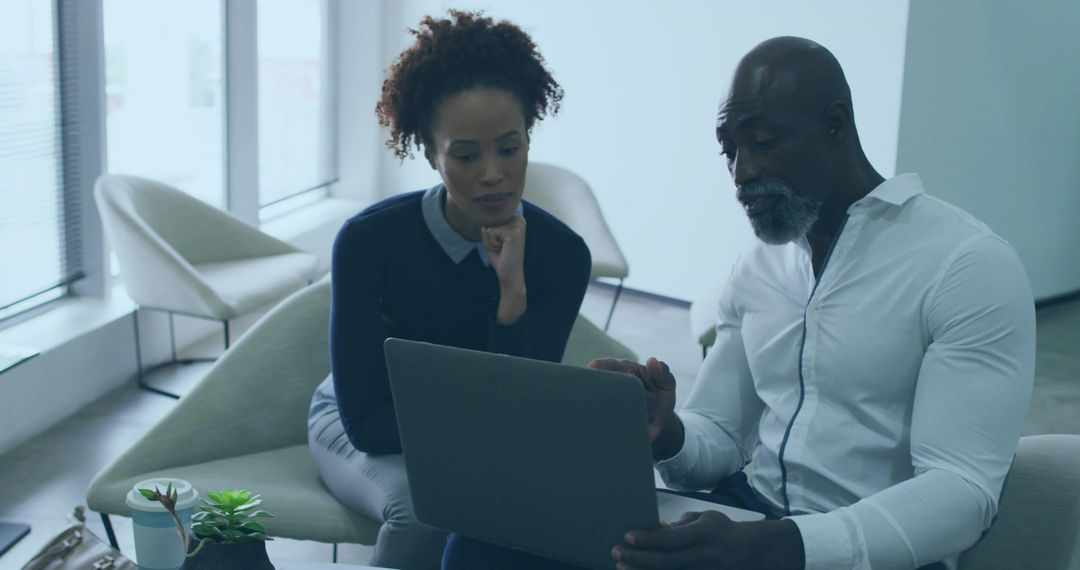 Professional Team Collaborating on Laptop in Modern Office Lounge