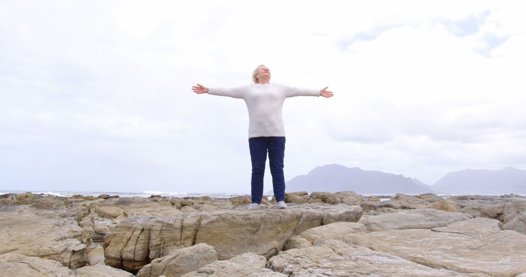 Senior Woman Spreading Arms in Freedom by Seaside Rocky Landscape - Free Images, Stock Photos and Pictures on Pikwizard.com