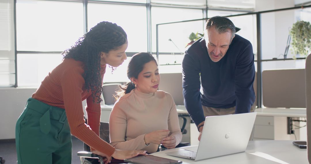 Multicultural Team Collaborating Over Laptop in Bright Open-Plan Office Discussing Strategy