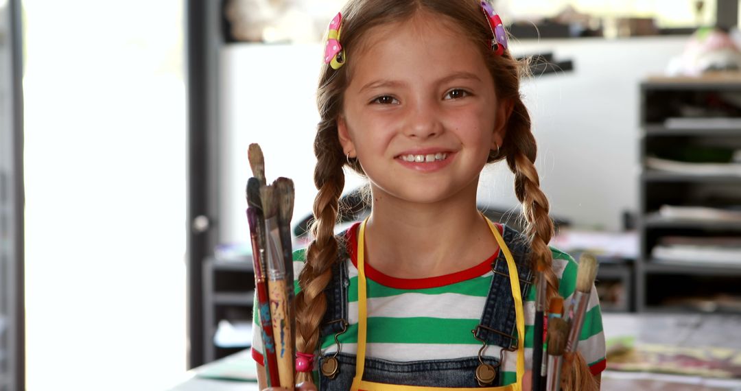 Young Artist Smiling with Paintbrushes in Studio