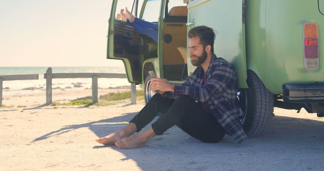 Man Relaxing by Camper Van at Beach, Messaging on Smartphone - Free Images, Stock Photos and Pictures on Pikwizard.com