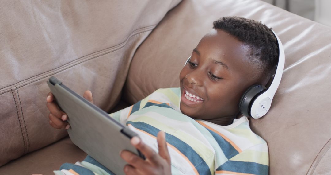 Smiling Boy Streaming Media on Tablet and Headphones