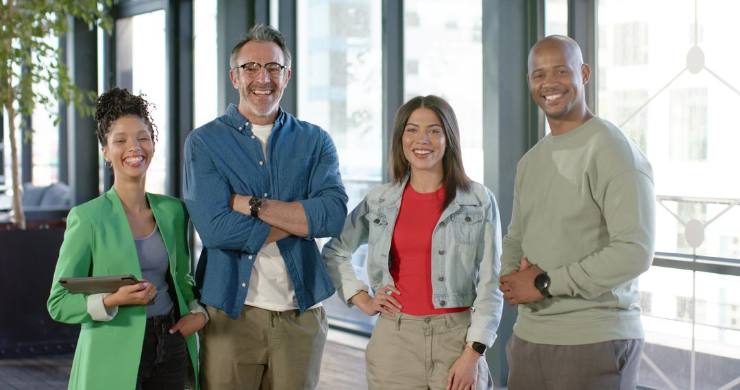 Diverse team smiling and collaborating in bright modern open-plan office with tablet
