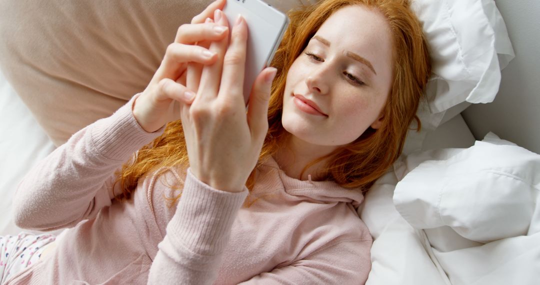 Young Redheaded Woman Relaxing in Bed and Using Smartphone - Free Images, Stock Photos and Pictures on Pikwizard.com