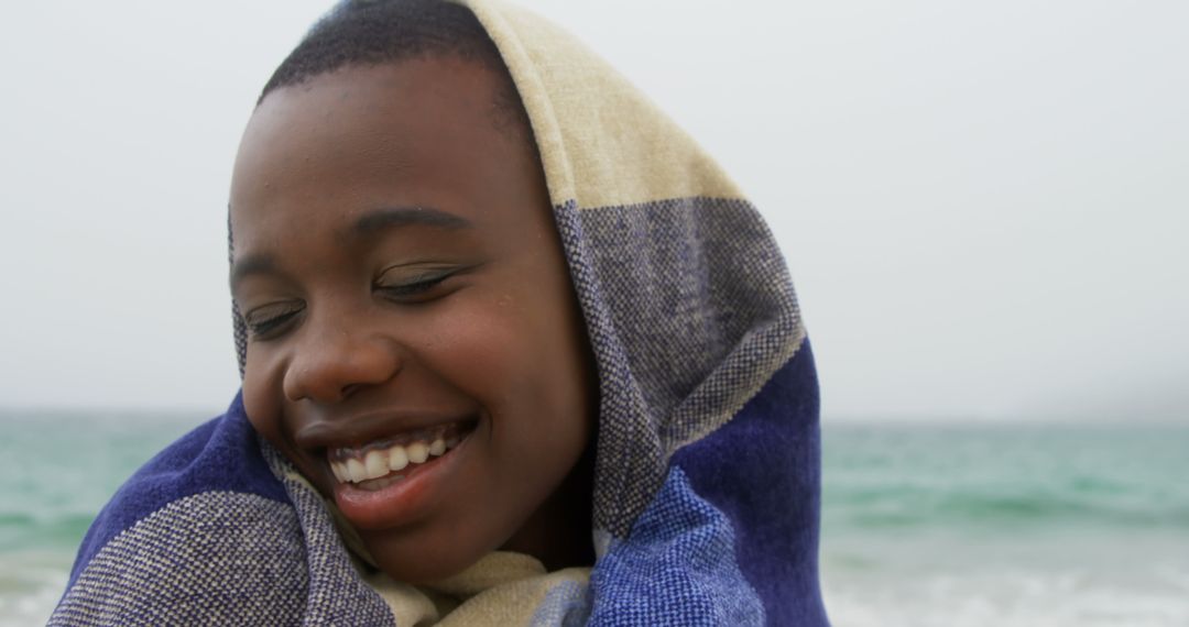 Smiling Woman Wrapped in Blanket on Beach