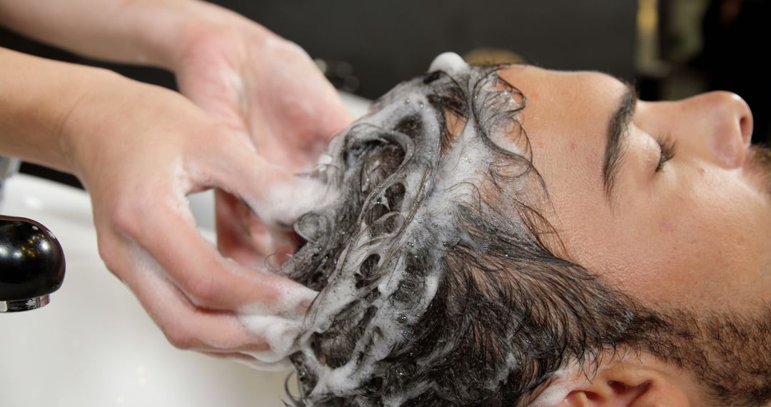 A young Caucasian man is getting his hair washed at a salon by a professional, with copy space - Free Images, Stock Photos and Pictures on Pikwizard.com