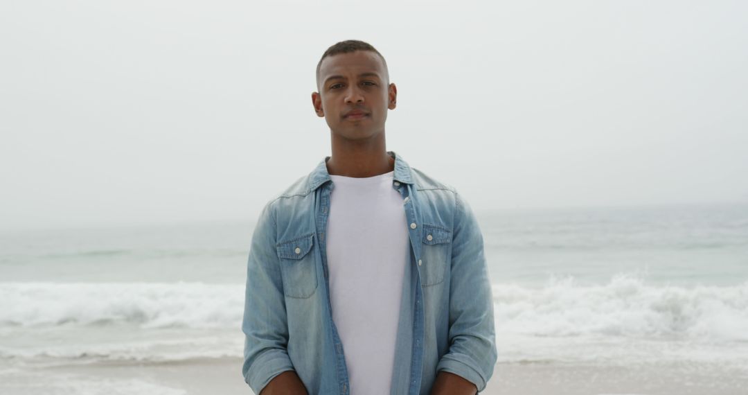 Confident Young Man Standing on Beach by Ocean - Free Images, Stock Photos and Pictures on Pikwizard.com