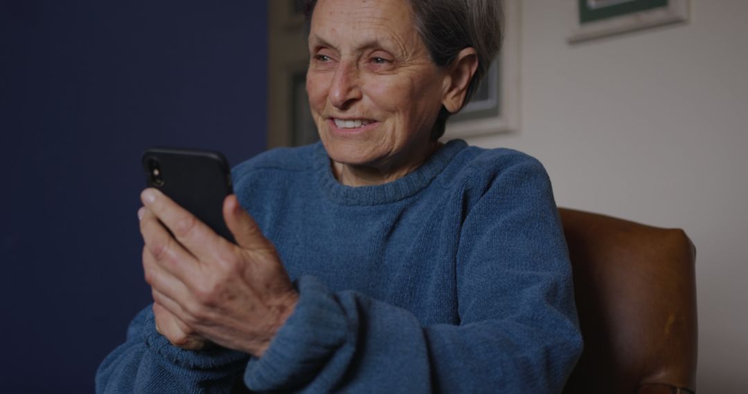 Senior Woman Smiling and Using Smartphone in Living Room - Free Images, Stock Photos and Pictures on Pikwizard.com