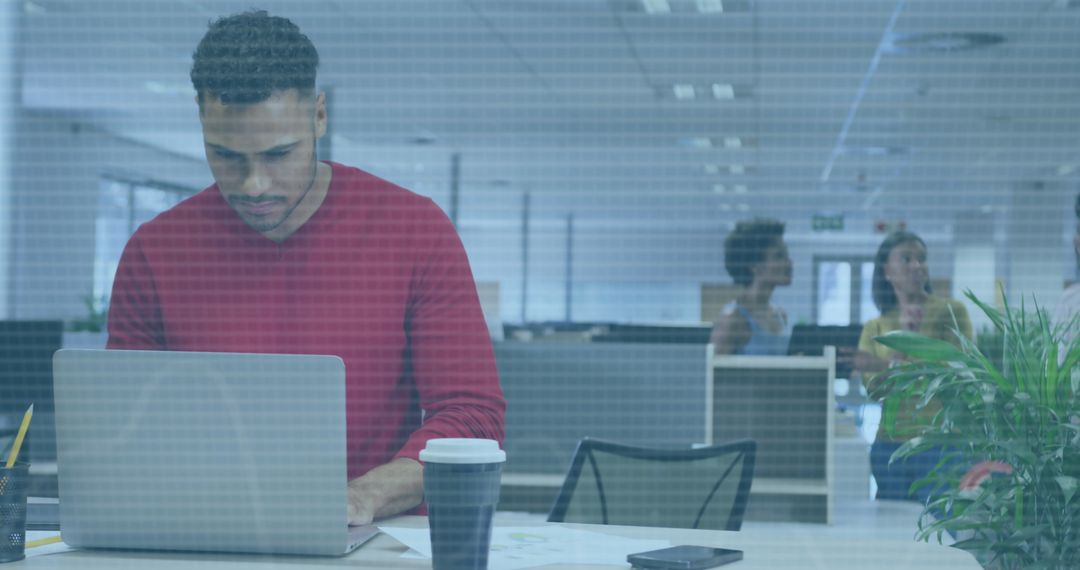 Biracial Businessman Analyzing Data on Laptop in Modern Office