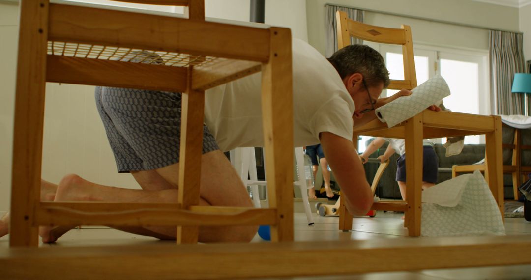 Father Cleaning Chair While Kids Play Indoors - Free Images, Stock Photos and Pictures on Pikwizard.com