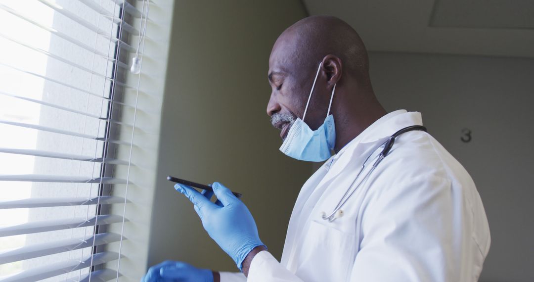 Doctor Using Smartphone Near Windowwith Mask - Free Images, Stock Photos and Pictures on Pikwizard.com