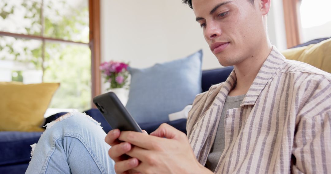 Biracial Man Engaging with Smartphone in Cozy Living Space
