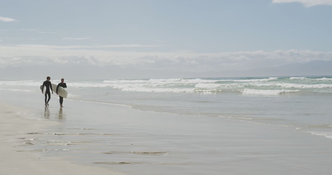 Two Surfers Walking on Sunny Beach with Surfboards - Free Images, Stock Photos and Pictures on Pikwizard.com