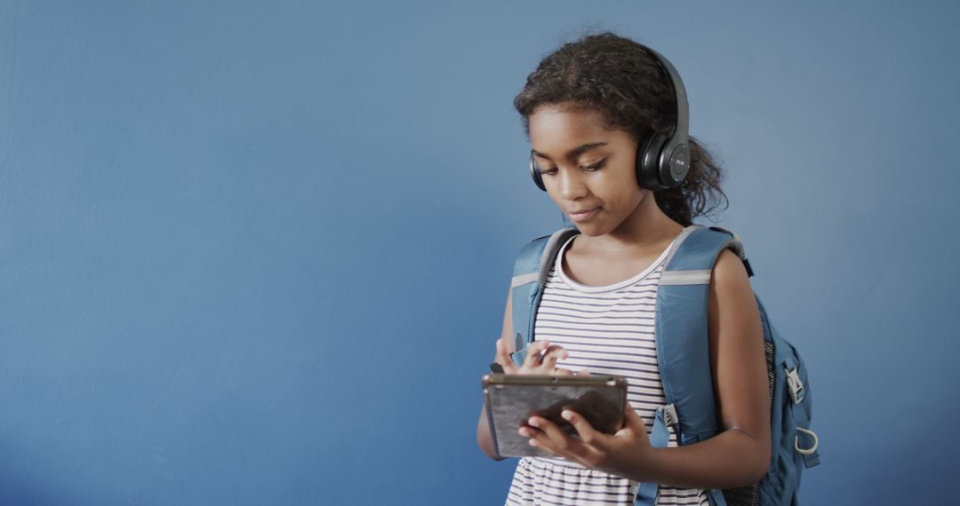 Afro-American Girl in Striped Shirt Using Tablet with Headphones - Free Images, Stock Photos and Pictures on Pikwizard.com