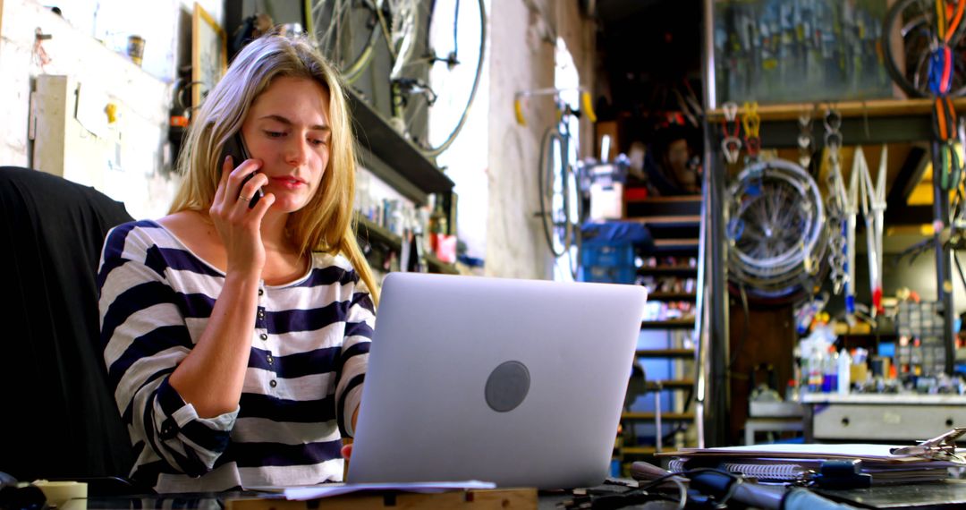 Woman Multitasking in Creative Workshop, Laptop and Phone Efficient Management