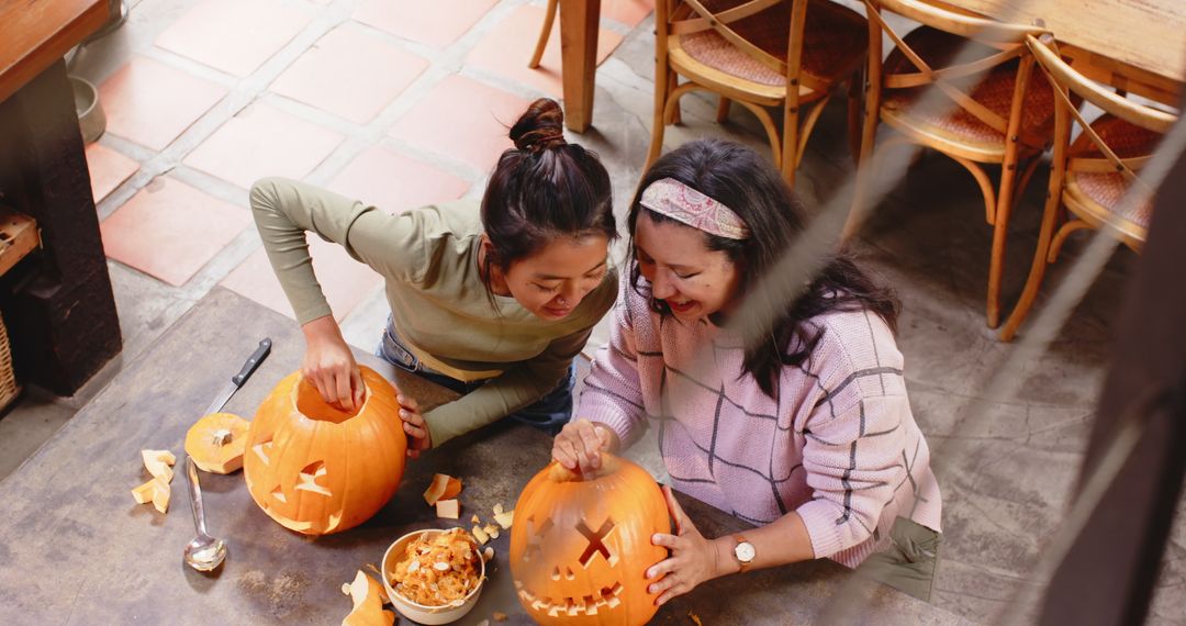 Multiracial Grandmother and Young Woman Carving Pumpkins for Halloween