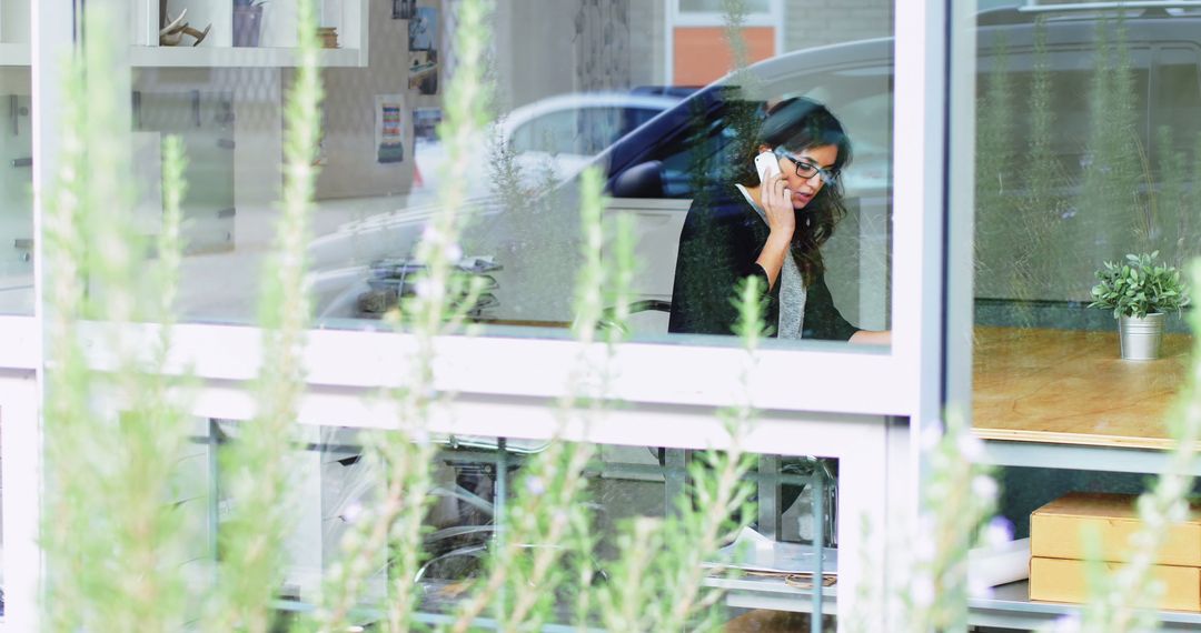 Businesswoman on Phone in Modern Office with Greenery Outside - Free Images, Stock Photos and Pictures on Pikwizard.com