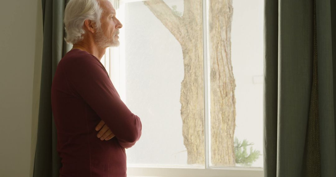 Contemplative Senior Man Looking Out Window in Thoughtful Reflection - Free Images, Stock Photos and Pictures on Pikwizard.com