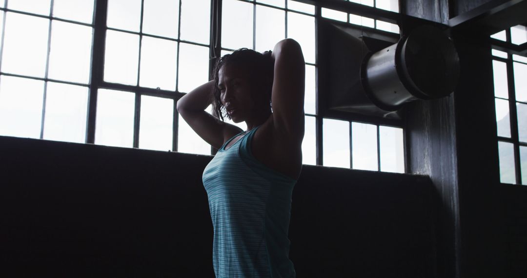 Woman Stretching Inside Industrial Gym with Large Windows - Free Images, Stock Photos and Pictures on Pikwizard.com