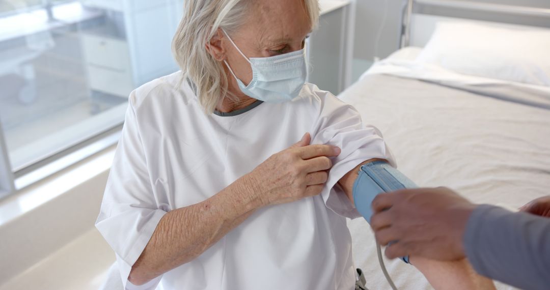 Senior Woman Wearing Mask Getting Blood Pressure Checked in Hospital - Free Images, Stock Photos and Pictures on Pikwizard.com