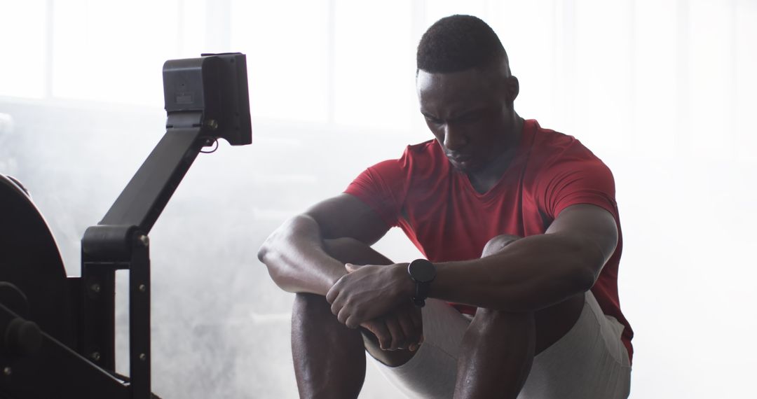 Man Resting on Exercise Machine in Modern Gym Setting