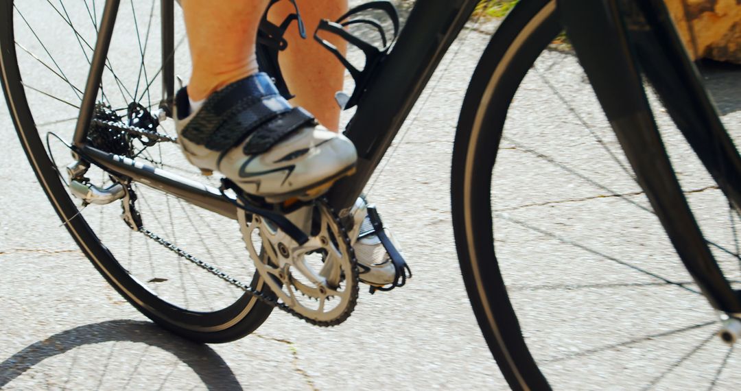 Cyclist's feet pedaling on road bike - Free Images, Stock Photos and Pictures on Pikwizard.com