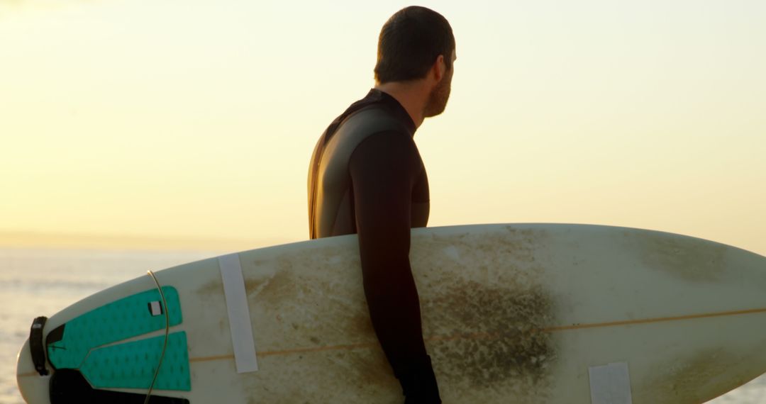 Surfer Holding Board at Sunset Beach Ready to Catch Waves - Free Images, Stock Photos and Pictures on Pikwizard.com