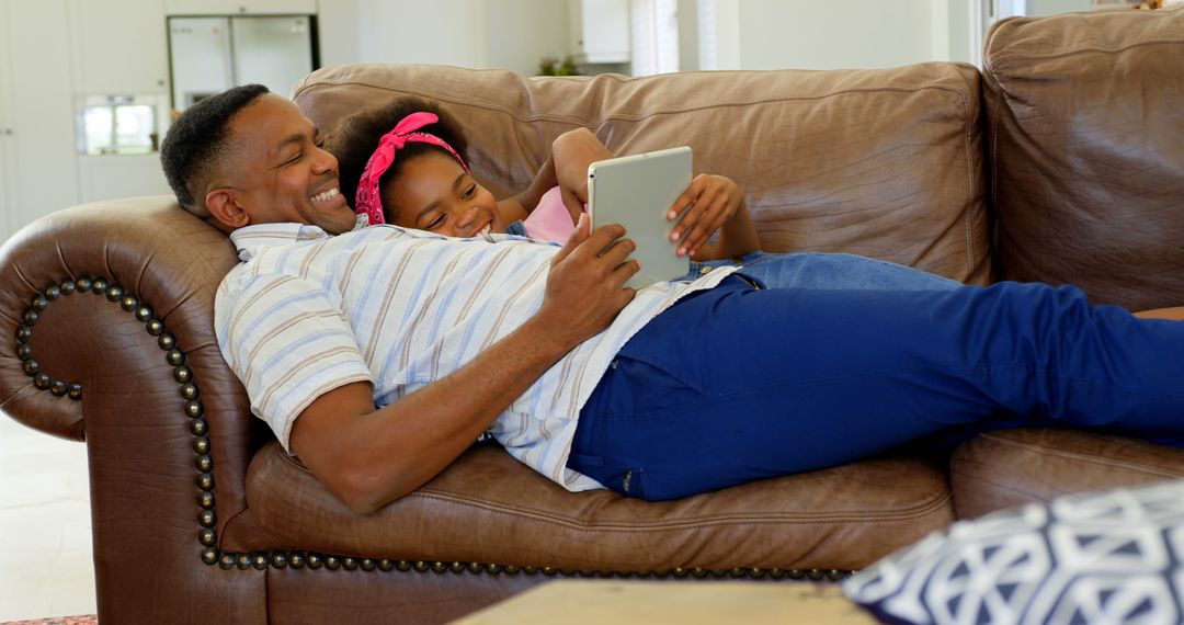 Father and Daughter Relaxing on Couch Using Tablet - Free Images, Stock Photos and Pictures on Pikwizard.com