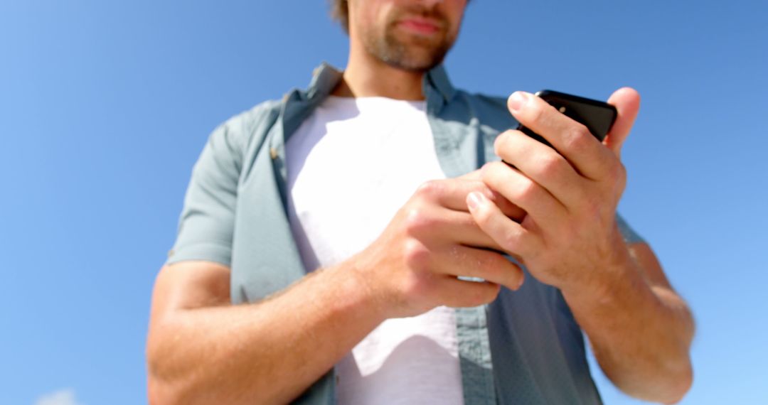 Man Using Smartphone Outdoors on a Sunny Day - Free Images, Stock Photos and Pictures on Pikwizard.com