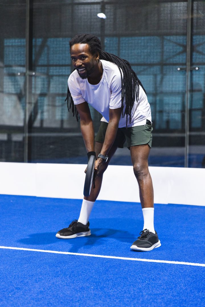 Crouching Man Gripping Padel Racket on Blue Court