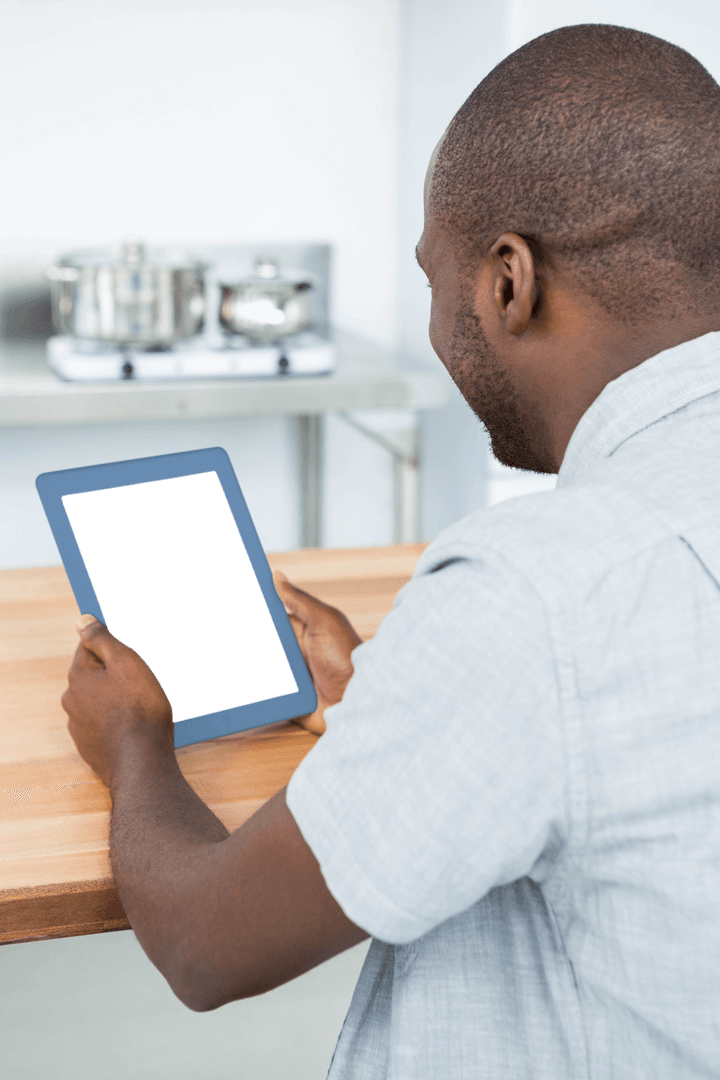 Man Viewing Transparent Tablet Screen at Wooden Kitchen Table
