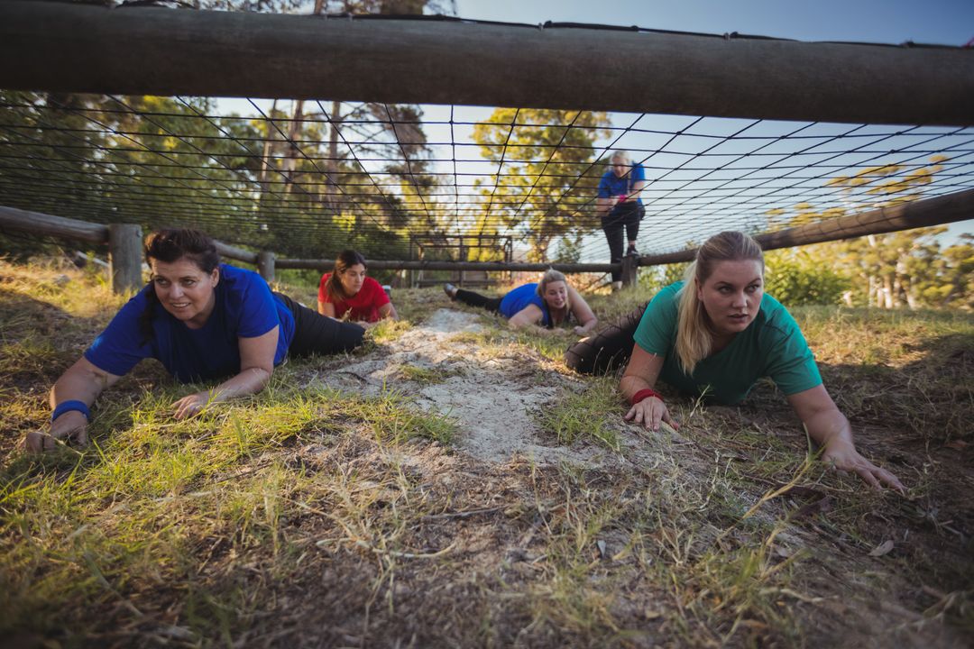 Group of fit women crawling under the net during obstacle course training - Free Images, Stock Photos and Pictures on Pikwizard.com