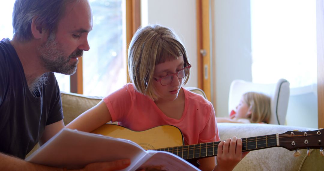 Father Teaching Daughter To Play Guitar In Cozy Living Room - Free Images, Stock Photos and Pictures on Pikwizard.com