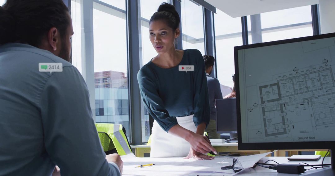 Leading architectural review, woman pointing at blueprints in modern daylight office