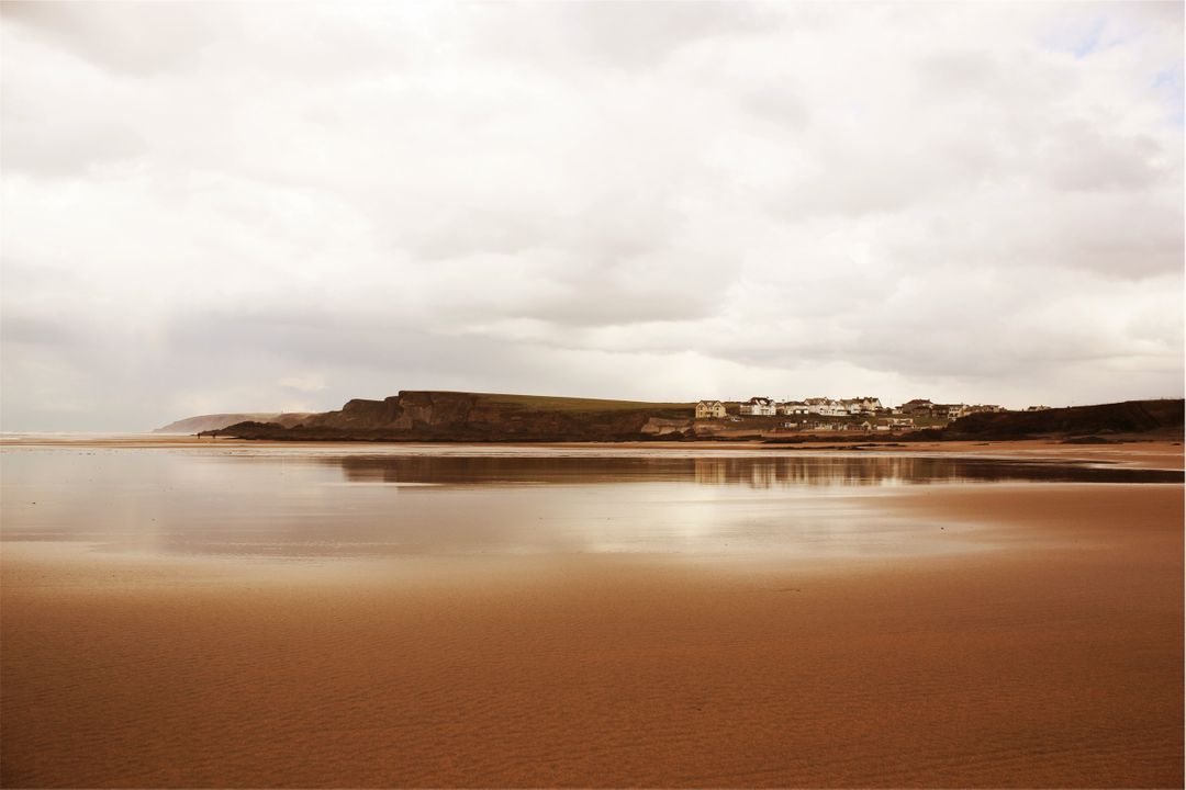 Serene Coastal Landscape at Low Tide with Distant Cliffs and Buildings - Free Images, Stock Photos and Pictures on Pikwizard.com