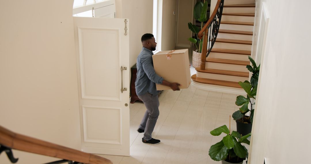 Man Carrying Cardboard Box in Elegant Entrance Hallway