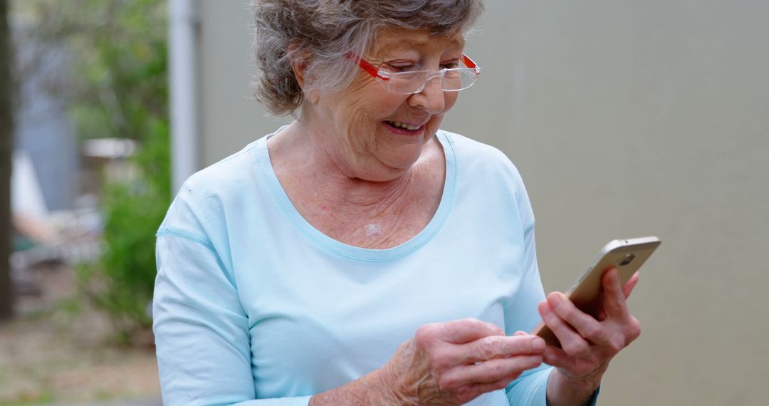 Smiling Elderly Woman Using Smartphone Outdoors - Free Images, Stock Photos and Pictures on Pikwizard.com