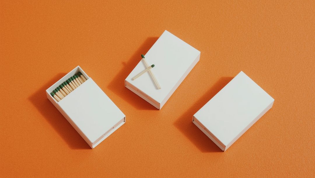 Minimalist Matchboxes on Orange Background with Green Matches